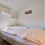 Ein Bett mit weißer Bettwäsche, ein Fenster und eine Wandlampe.