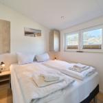Ein Schlafzimmer mit Doppelbett, Fenster und Nachttisch.