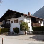 Wohnhaus mit Balkonen und Gartenzaun vor Berglandschaft
