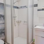 Badezimmer mit Dusche, Waschbecken und Toilette. Fliesen mit blau-weißem Muster.