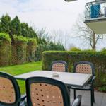 Hinterhof mit Tisch und Stühlen, umgeben von Hecke und Zaun.