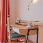 Schreibtisch mit Stuhl und Stehlampe neben Fenster mit Blick auf Garten