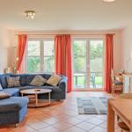 Wohnzimmer mit Sofa, TV und Terrasse. Rote Vorhänge und Holzmöbel.