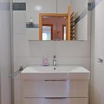 Badezimmer mit Waschbecken, Spiegel und Dusche