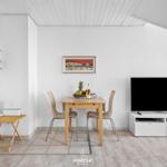 Essbereich mit Tisch, zwei Stühlen und Fernseher auf weißem Sideboard.
