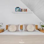 Schlafzimmer mit Dachschrägen, Bett, Nachttischen und Regal mit Büchern.