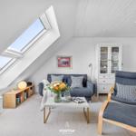 Wohnbereich mit Sofa, Sessel und Blick durch Dachfenster