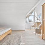 Schlafzimmer mit Holzbett, Kleiderschrank und Fenster mit Blick.
