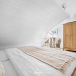 Schlafzimmer mit Dachschrägen, Bett, Kleiderschrank und Stühlen.
