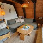 Living room with sofa, armchair, wooden table, and wood wall