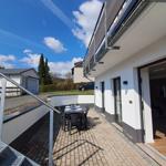 Terrasse mit Tisch und Stühlen neben Wohnhaus mit Eingang.