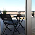 Terrasse mit Stuhl und Tisch, Pflanzen und Blick auf Dächer.