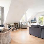 Wohnbereich mit Sofa, Esstisch und TV unter Dachschrägen.