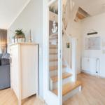 Eingangsbereich mit Treppe und Wohnzimmer mit Sofa und Fenster.