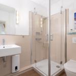 Bad mit Dusche, Waschbecken und Toilette. Wandbild und Spiegel sind sichtbar.