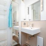 Badezimmer mit Waschbecken, Spiegel und Dusche