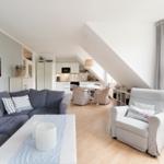 Wohnzimmer mit Sofa, Sessel und Essbereich unter Dachschräge.
