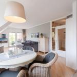 Wohn- und Essbereich mit Esstisch, Sesseln und Sofa. Durchgang zur Küche und Schlafzimmer.
