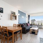 Wohn- und Essbereich mit Sofa, Tisch und Stühlen. Balkon mit Blick. Wanddekoration.