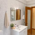 Bathroom with sink, mirror, shower, and toilet. Walls with floral tile pattern.