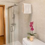 Shower with glass enclosure, towel rack, and plants on washing machine.