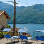 Terrace with three blue lounge chairs and view of lake and mountains.