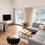 Wohn- und Essbereich mit Sofa, Tisch und TV. Durchgangstür zur Terrasse.