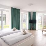 Zimmer mit zwei Betten, grünen Vorhängen und großem Fensterblick auf Außenbereich.