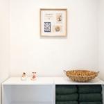 Wand mit Bild, weißer Schrank mit Handtuchstapel und Körbchen.