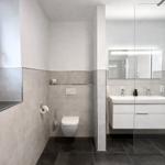 Badezimmer mit WC, Waschbecken und Spiegel. Fenster mit Vogeldekoration.