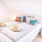 Schlafzimmer mit Doppelbett, Kissen und Handtüchern. Fenster und Nachttisch sind sichtbar.
