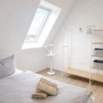 Schlafzimmer mit Dachschräge, Bett, Kleiderständer und Fenster.