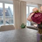 Tisch mit Blumenarrangement und Blick auf Balkon mit Sitzgelegenheiten.