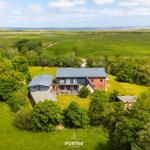 Modernes Haus mit Terrasse, umgeben von Grünland und Wald, Blick auf die Nordsee.