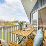Terrasse mit Tisch, Stühlen und Blick auf Wohngebiet und Hochhaus.