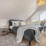 Schlafzimmer mit Dachschräge, Bett, Fenster und Stuhl.