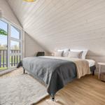 Schlafzimmer mit Bett, Nachttisch und Fenster zur Terrasse.