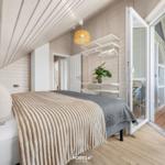Schlafzimmer mit Bett, Schrank und Balkonanschluss. Holzwände und Dachschrägen.