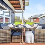 Terrasse mit Sitzgruppe, Tisch und Blumen. Holzdecke und Gartenblick.