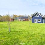 Ein blaues Haus mit weißem Fensterrahmen steht auf einer grünen Wiese.