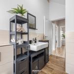 Badezimmer mit Waschbecken, Regal und Heizung. Holzboden und hellbeige Fliesen.