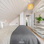 Schlafzimmer mit Bett, Kleiderschrank und Decke. Holzwände und Decke. Lampe und Pflanze.