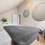 Schlafzimmer mit Bett, Wandspiegel und Deckenleuchte.