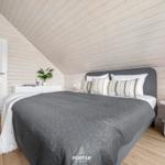Schlafzimmer mit Dachschrägen, Bett, Nachttisch und Pflanze.