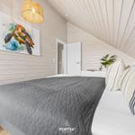 Schlafzimmer mit Bett, Wandbild und Deckenleuchte. Holzwände und schräge Decke.