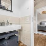 Badezimmer mit Waschbecken und Blick in das Schlafzimmer mit Bett und Decke.