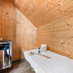 Sauna mit Holzwand, Liege, Dampferzeuger und Badematten.