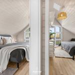 Zwei Schlafzimmer mit Dachschrägen, Holzboden und Fenstern zur Aussicht.