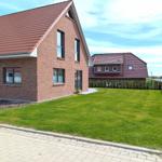 Zweistöckiges Haus mit rotem Dach und grünem Rasen vorne.