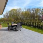 Terrasse mit Tisch und Stühlen, umgeben von Grün und Bäumen.